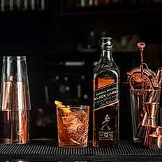 Old Fashioned cocktail in a glass next to a bottle of Whiskey